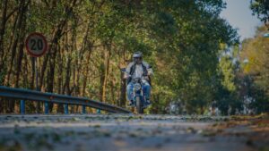 man riding scooter down forest road