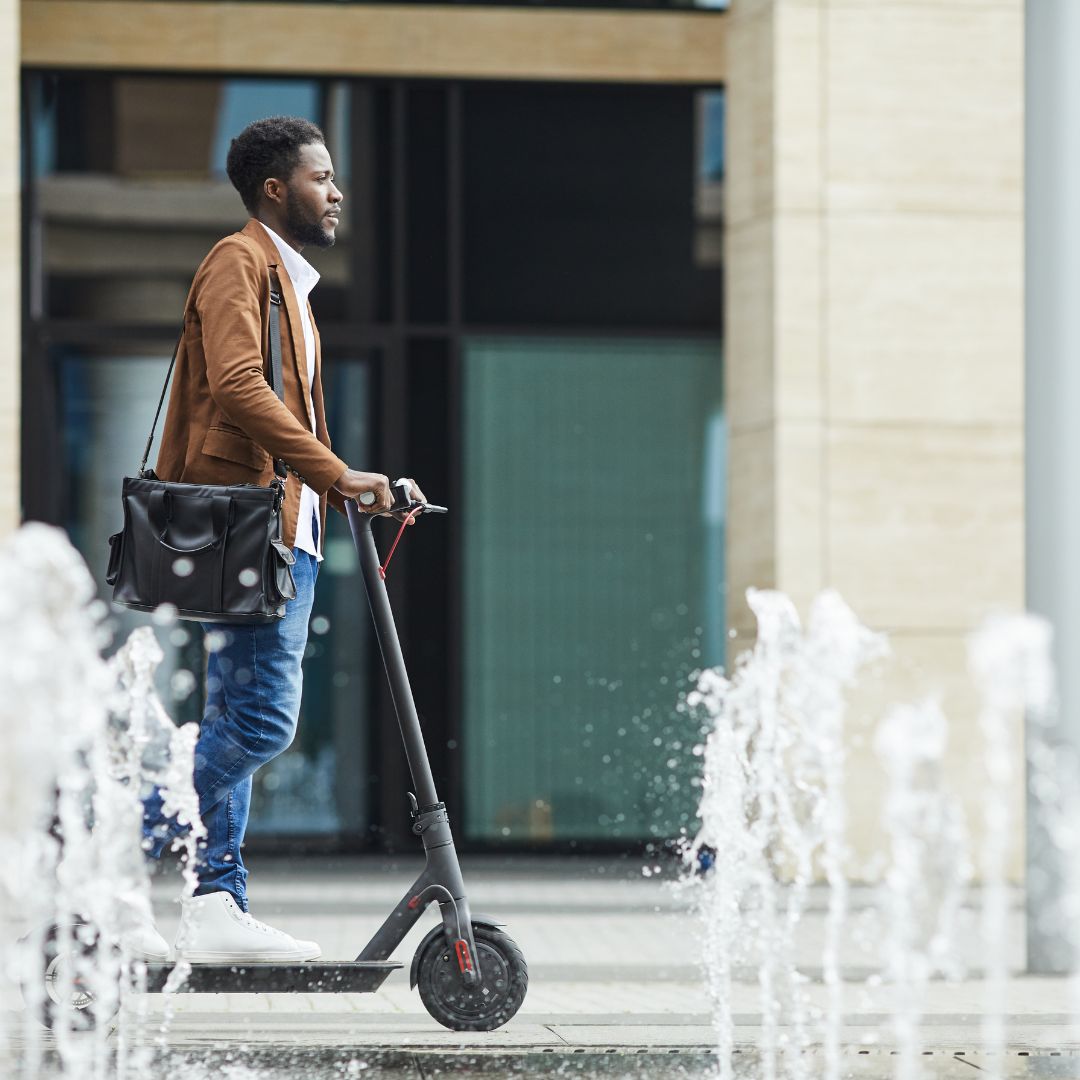 Businessman riding scooter by fountain